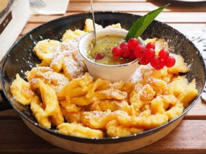 a bowl of food with a spoon and a sauce "Kaiserschmarrn"